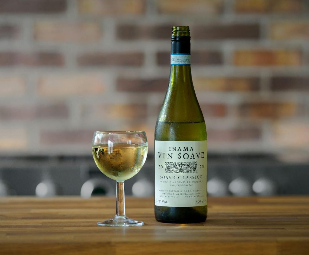 Selective Focus of Inama Vin Soave Bottle and a Wine Glass on Wooden Surface